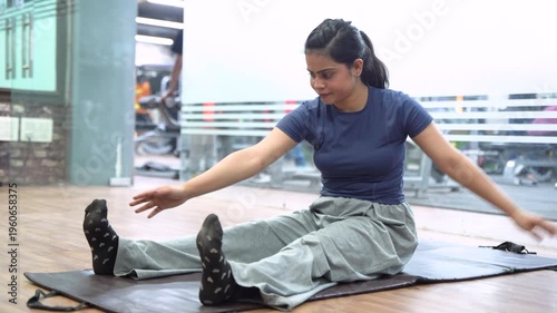 Indian Woman Performing Seated Hamstring Stretch Exercise During Workout in Gym