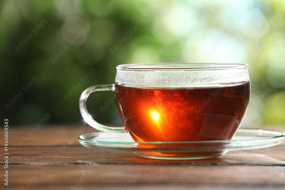 Fototapeta premium Aromatic tea in glass cup on table outdoors, closeup