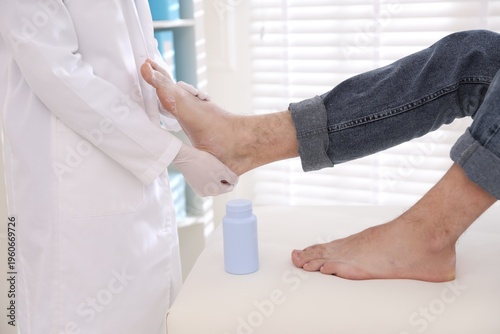 Obraz na plátne Doctor applying talcum powder onto man's foot in clinic, closeup
