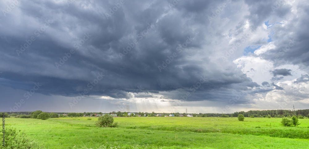 Naklejka premium Dark clouds loom over vast green fields