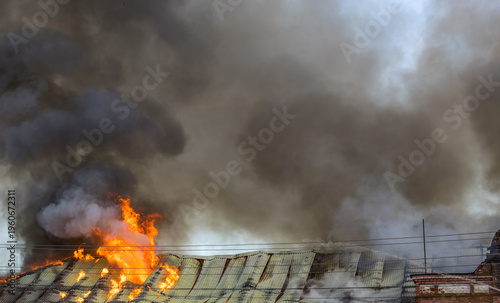 Konstfotografi Intense flames engulf a roof, sending thick black smoke into the sky