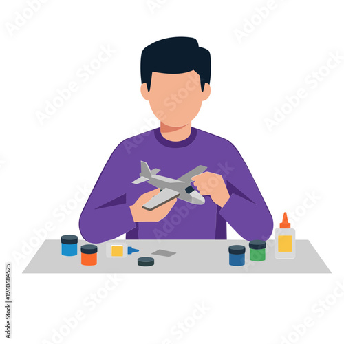 A man is painting a model airplane with various colors on a table indoors.