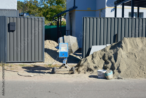 Repair work in the courtyard of the house. Сement pile and concrete mixer at the entrance to the house for construction or repair work
