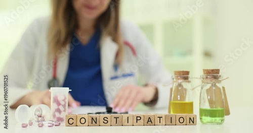 Wooden blocks spell word Constipation near herbal bottles and tablets. Doctor woman explains bowel problem planning diet change and laxative use