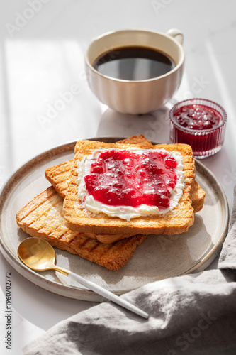 Toast with sweet berry-fruit jam and cream cheese on a plate on a white marble background