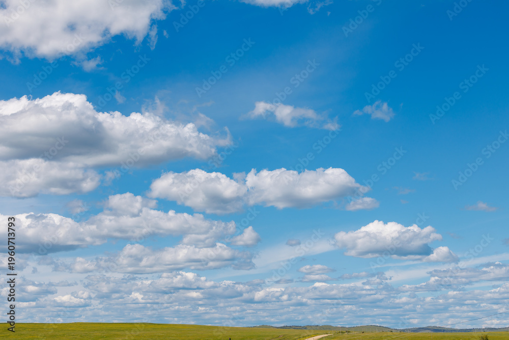 Fototapeta premium Blue sky filled with scattered clouds over open prairie