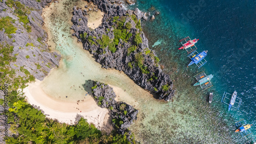 A top-down drone perspective revealing a magnificent lagoon and beach in El Nido, Philippines. Karst cliffs and crystal-clear waters characterize this iconic Palawan location.