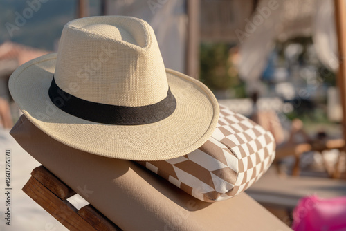Foto Straw hat resting on lounge chair at a beachside terrace with soft sunlight, rel