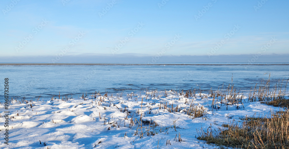 Fototapeta premium Landscape, blue sky and ocean with snow in nature for climate change, winter season and morning frost. Space, grassland and seaside with ice formation, snowfall and icy conditions from global warning