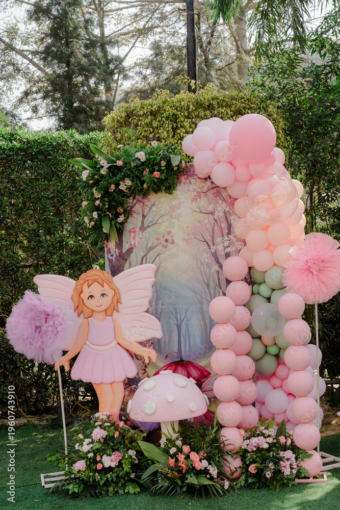 Obraz premium Enchanting outdoor birthday party decor with a fairy cutout, balloons, and floral arrangement in a lush garden setting
