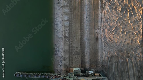 bucket chain excavator massive piece of industrial equipment typically used in open-pit mining or large-scale dredging. operating at edge of water body, likely excavating material from shoreline or fl