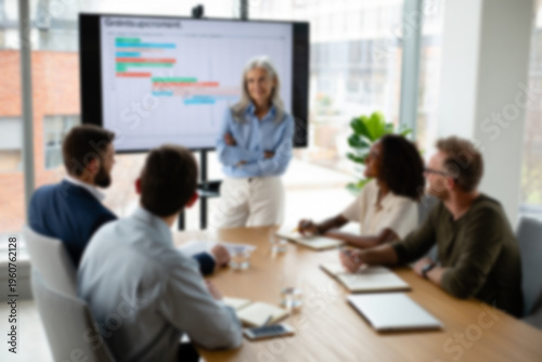 soft focus blurred photo of Professional business presentation in modern office, senior female leader presenting project timeline to diverse corporate team, blurred office meeting