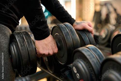 Person picking up dumbbell from rack in gym