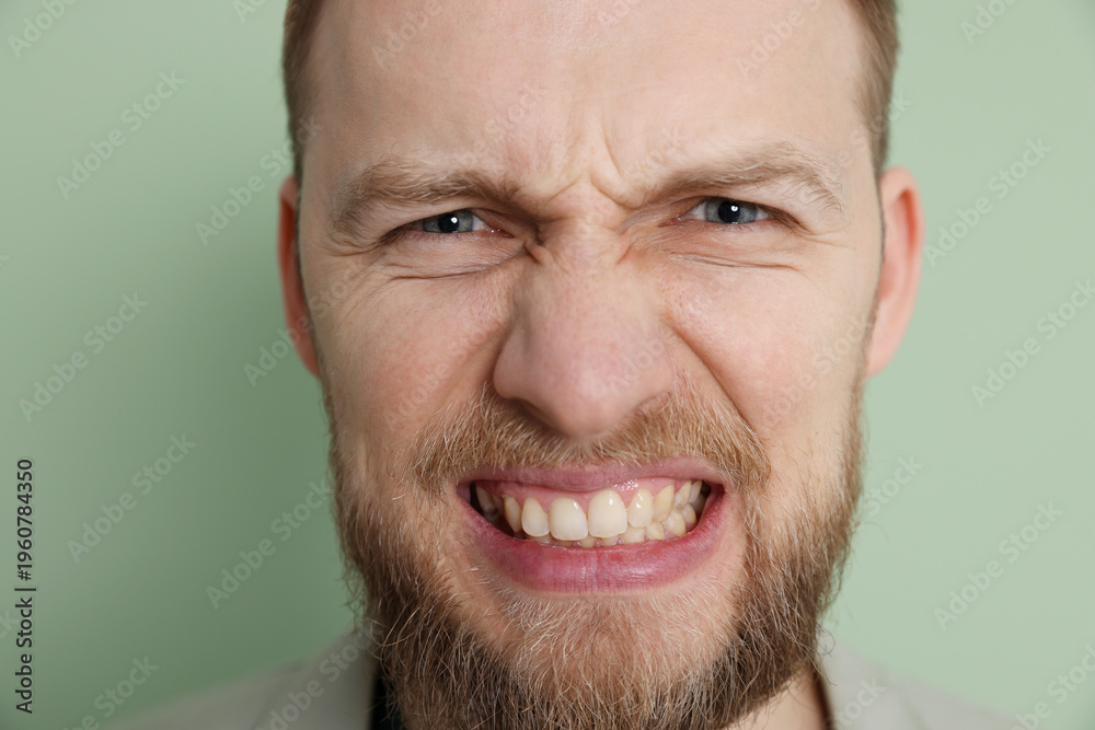 Obraz premium Resentful man on light green background, closeup