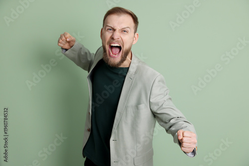 Картината върху платно Resentful man in suit screaming and showing fists on light green background