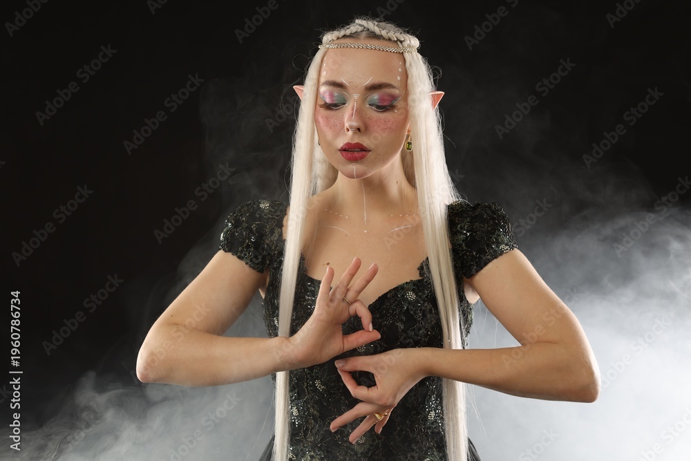 Obraz premium Beautiful girl dressed as elf on black background with smoke