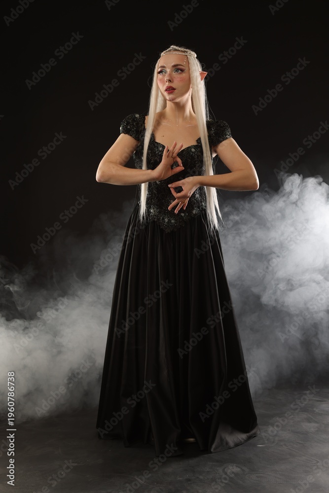 Obraz premium Beautiful girl dressed as elf on black background with smoke