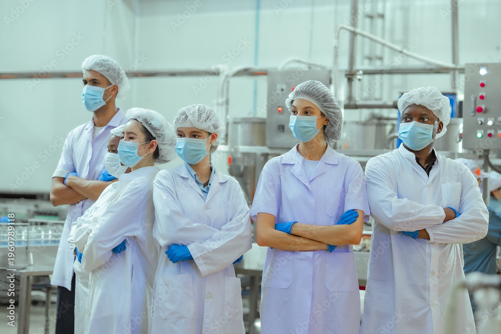 Obraz premium Processing plant workers gather in canned fish facility observing workflow and machinery performance. Image represents production oversight, quality inspection and organized factory management.