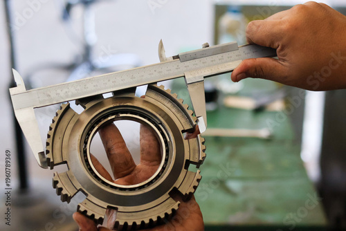 Slika na platnu Mechanic hands measuring a steel synchronizer gear using manual vernier caliper in a workshop to check precision dimensions for automotive transmission repair
