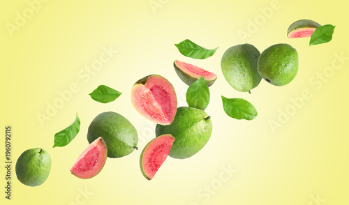 Fresh guava fruits and green leaves flying in air against beige background