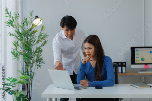 Картината върху платно Male manager points at laptop while female employee looks frustrated and confuse