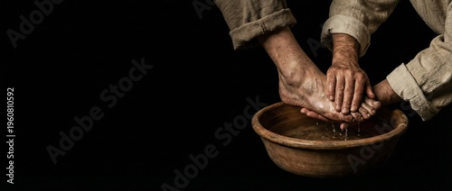 Jesus washing the feet of his disciple in a clay bowl. Biblical concept of Maundy Thursday, humility, and service. Dark background with copyspace