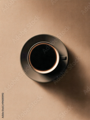 Top-down view of a steaming cup of black coffee in a dark saucer casting a long shadow on a textured beige surface creating a minimalist composition