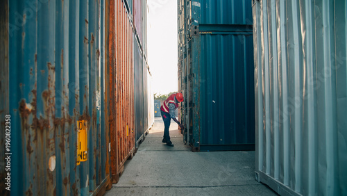 Worker safety vest hard hat shipping container logistics transportation outdoor warehouse manual labor industry worker safety vest and hard hat pushing shipping container door outdoor warehouse