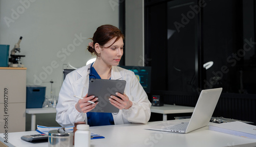 Doctor working on laptop and tablet and medical on clipboard on desk, electronics medical record system EMRs concept.