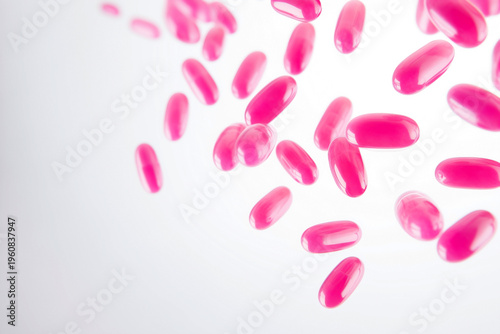 falling soaring pink medicine capsules on white background
