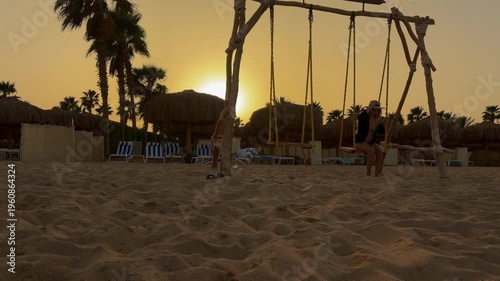 Sunset Silhouette On Sandy Shore. Relaxed Female Silhouette Swaying In Sunset Amidst Palm Trees