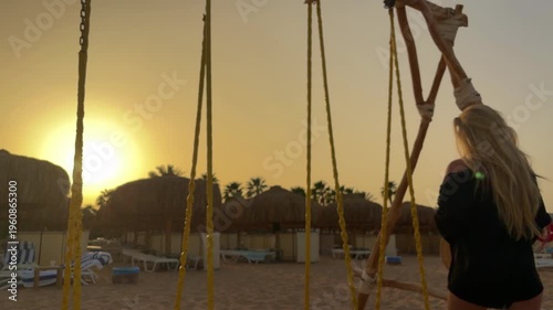 Sunset Scene With Woman On Swing. Caucasian Woman Perched On Swing At Sunset Beach