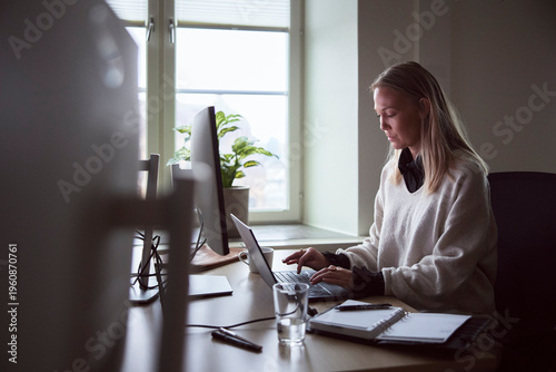 Female tech expert using laptop while working at desk in office