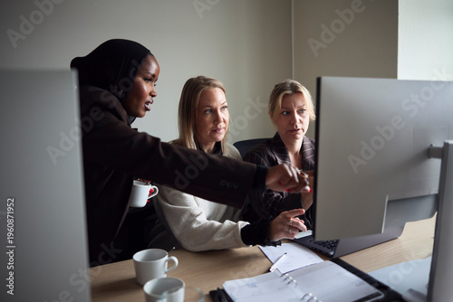 High angle view of multiracial female business professionals discussing ideas with each other on desktop PC in office