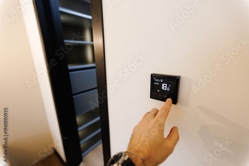 Tableau sur toile Individual modifies temperature setting on digital thermostat screen