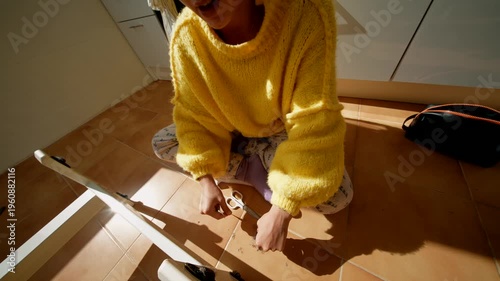 Young Lady Assembling Furniture Smoothly. Woman Tightening Screw On Wooden Chair In Sunlit Cozy Room