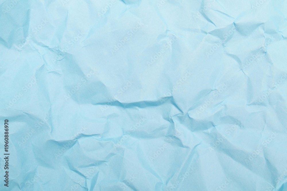 Fototapeta premium A blank sheet of crumpled blue paper features a rough creased texture and wrinkled grunge pattern across its damaged surface to create a unique old material backdrop for design art