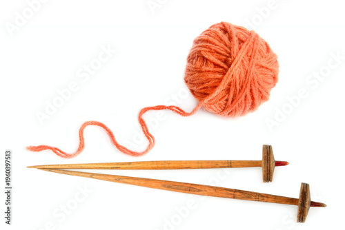 Top view of a ball of orange wool yarn with a loose thread and two vintage wooden spindles for spinning isolated on a white background, representing traditional handicraft and textile arts.