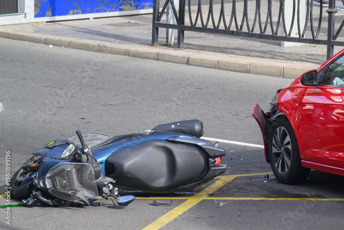 Close up of a car and motorcycle collision showing damage to the front bumper of a red car