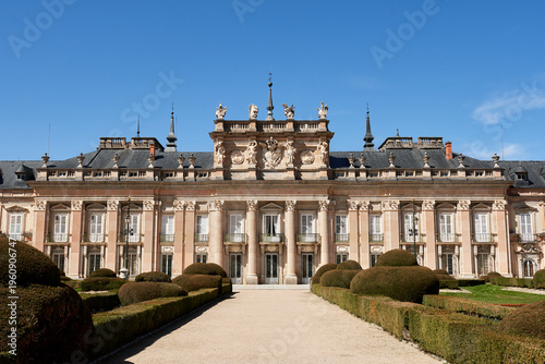 Front facade of the Royal Palace of La Granja de San Ildefonso surrounded by formal Baroque gardens in Segovia, Spain. Historic royal residence featuring elegant symmetry and classical architecture