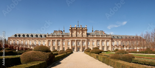 Wide panoramic view of the Royal Palace of La Granja de San Ildefonso surrounded by formal Baroque gardens in Segovia, Spain. Historic royal residence featuring elegant landscape design
