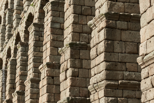 Close-up view of the ancient Roman Aqueduct of Segovia, showcasing massive granite stone blocks, arches, and architectural details. Historic landmark and UNESCO World Heritage Site in Spain.
