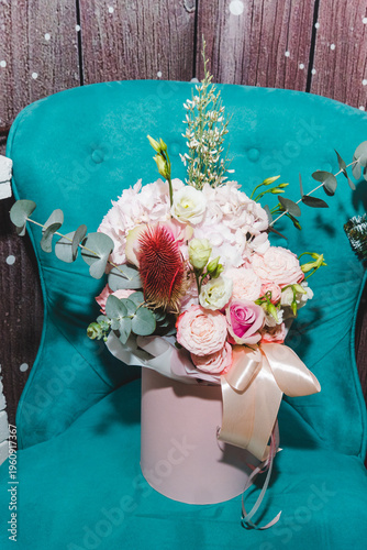 Flower arrangement in the interior. Beautiful bouquet on a turquoise chair. Floristry and floral design concept.