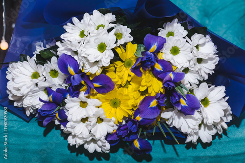 Flower arrangement background. Beautiful fragrant bouquet with white and yellow chrysanthemums, and blue irises. Floristry and floral design concept. Floral texture close-up.