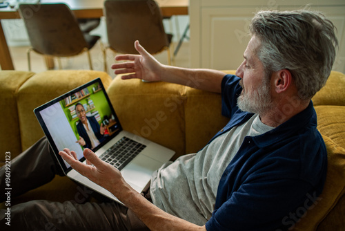 Older man video chatting on laptop at home