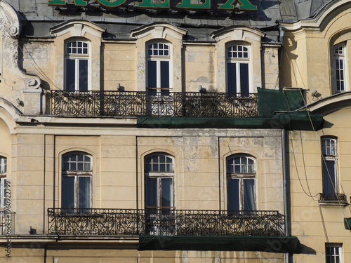 Historic yellow building facade with classic windows and wrought iron balconies