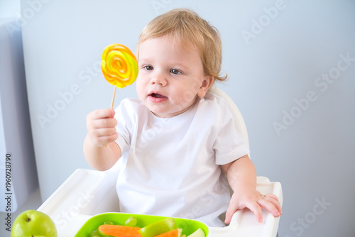 cute baby eating lollipop sitting in a baby chair. weaning