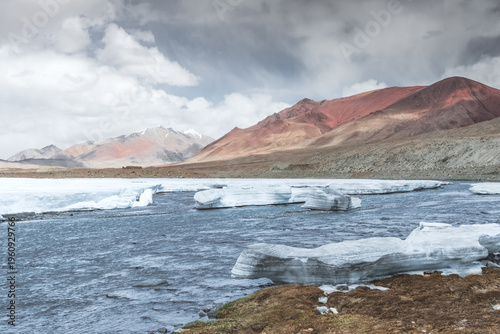 Massive snowdrifts and glaciers lie along the banks of a wide mountain river and melt in the highlands of Tajikistan's Pamirs against the backdrop of the Tien Shan mountain range
