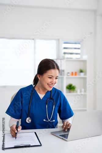Doctor working in office, using a laptop to access patient records on system. Mature physician using modern technology in her practice.