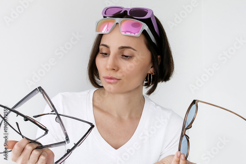 Photos Pensive Young Brunette Woman Holding Multiple Colorful Sunglasses While Wearing